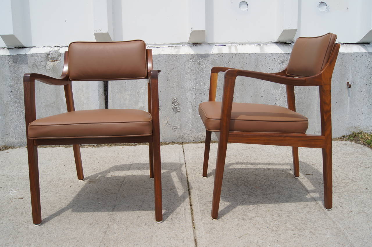 Designed by Edward Wormley for Dunbar, this handsome pair of armchairs features solid walnut frames whose curvaceous armrests contrast well with the strong lines of the legs. The seats have been reupholstered in a supple brown leather.