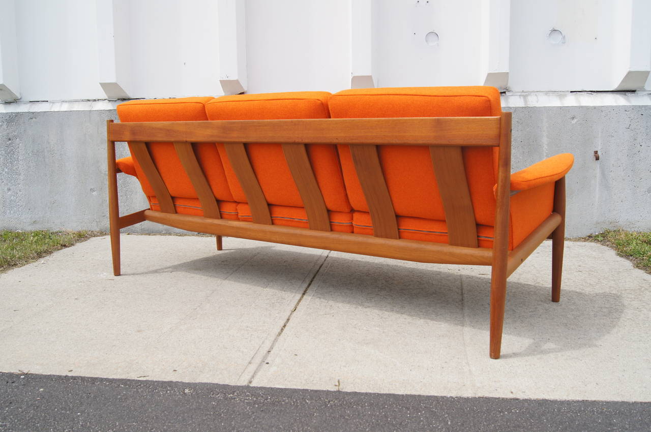 This sofa was designed by Grete Jalk and manufactured by Cado. It features an exposed teak frame and seats that have been reupholstered in Maharam's Hallingdal textile.