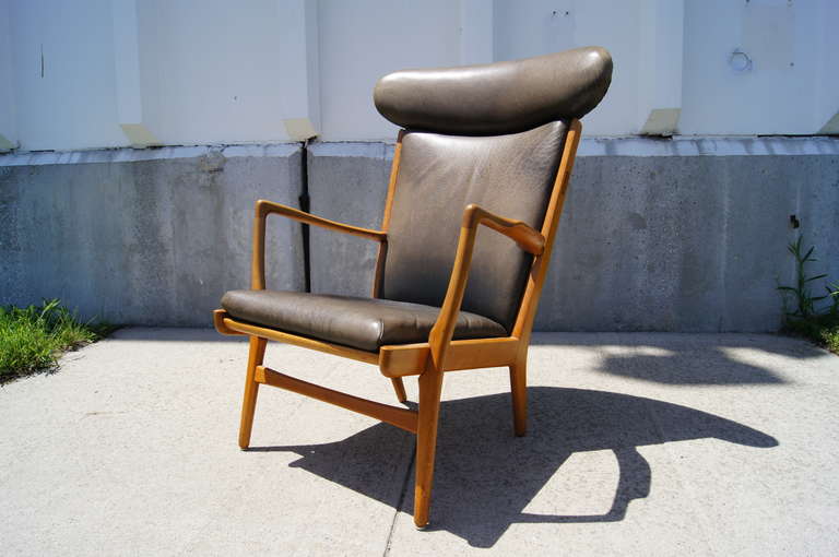 This chair was designed by Hans Wegner in 1951 and manufactured by AP Stolen. It is composed of an oak frame with dark grey leather upholstery. The leather is well-aged with a beautiful texture and patina.
