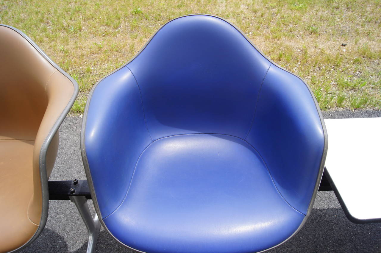 Charles and Ray Eames developed this tandem shell seating for Herman Miller in 1963 as a comfortable solution for heavily trafficked spaces. A row of four vinyl-upholstered fiberglass-reinforced armchairs, alternating raw umber and ultramarine,