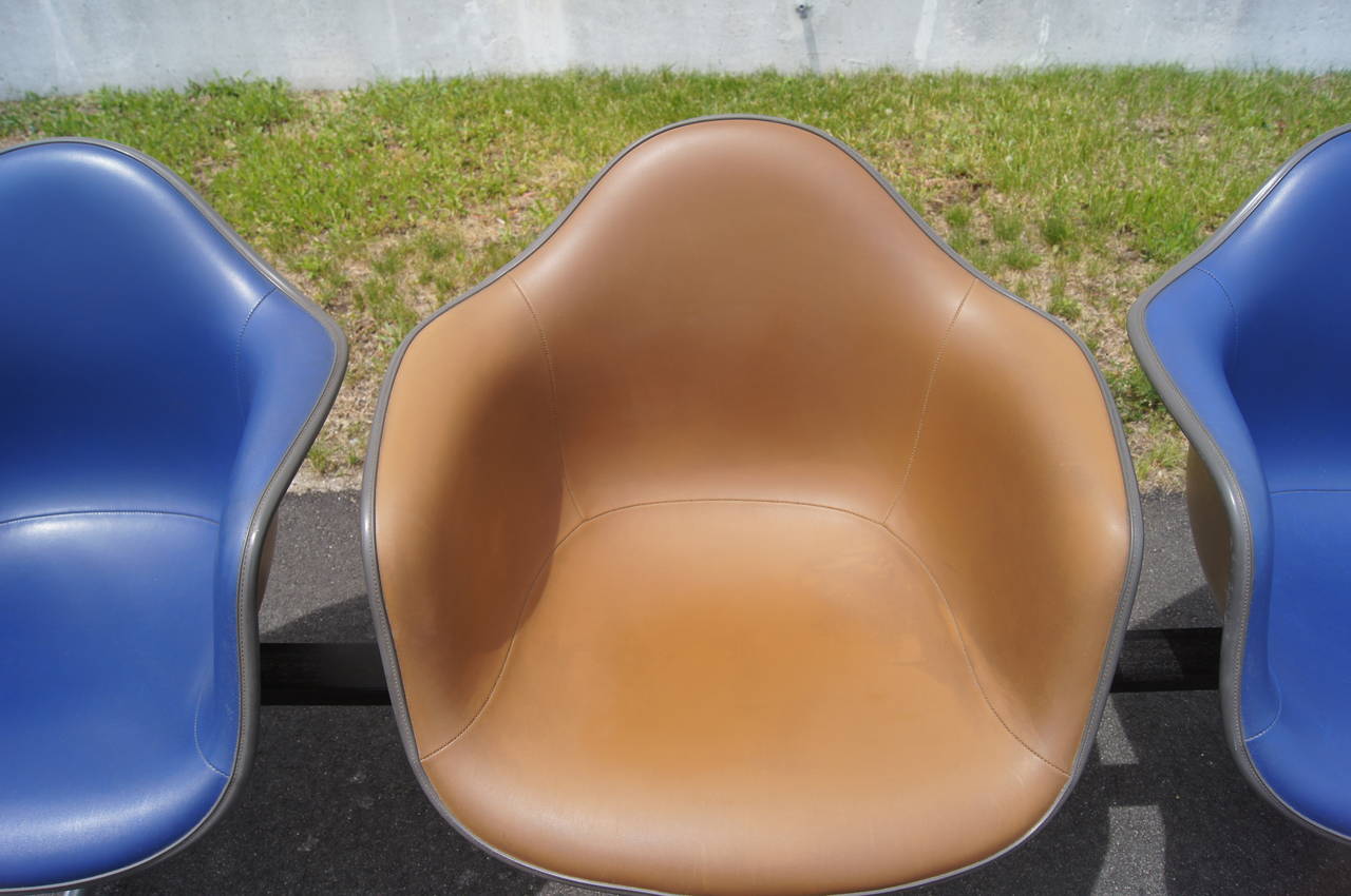 Charles and Ray Eames developed this tandem shell seating for Herman Miller in 1963 as a comfortable solution for heavily trafficked spaces. A row of three vinyl-upholstered fiberglass-reinforced armchairs, two in ultramarine and one in raw umber,