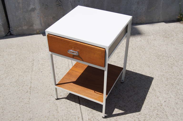 This nightstand by George Nelson for Herman Miller is constructed of an enameled steel frame with a wood shelf and a wood-front drawer. The drawer features three small compartments and the original manufacturer's label.