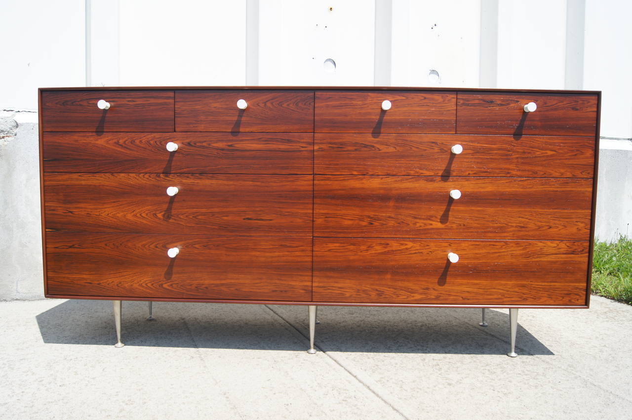 This beautiful chest of drawers, designed in 1952 by George Nelson and manufactured by Herman Miller in 1955, showcases a stunning rosewood grain and the original white porcelain pulls. Its especially thin-edged case sits on tapered aluminium legs.