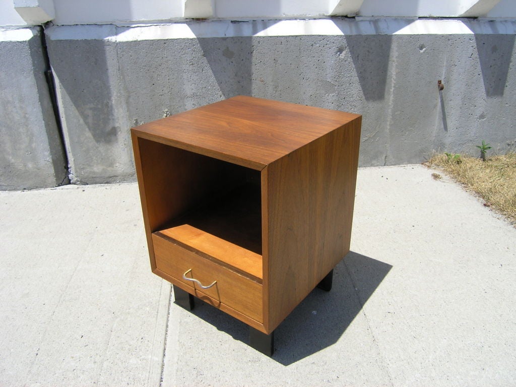 Walnut night stand with open compartment and one drawer standing on rectangular black legs.