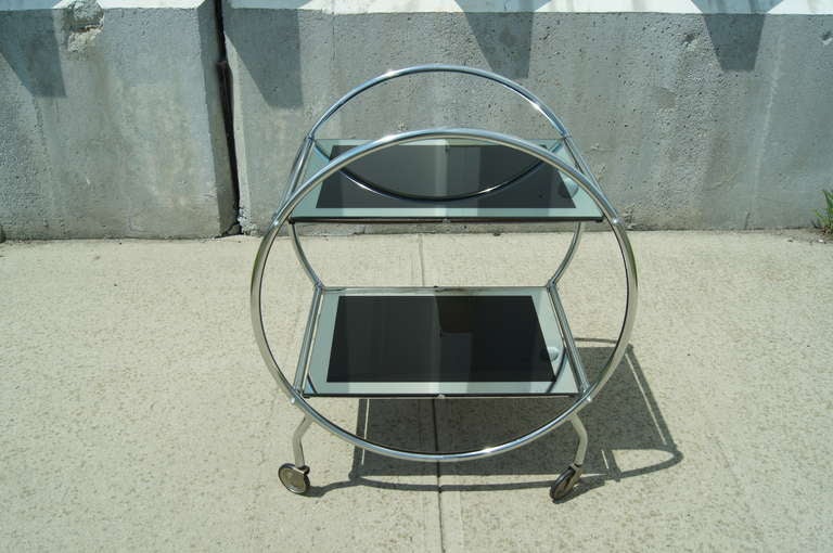 This art deco cart is composed of a circular chrome frame with two mirrored and black glass shelves.