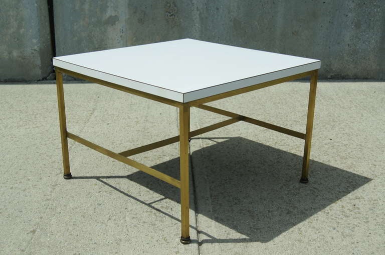This small end or side table by Paul McCobb is composed of a white formica top on a brass base.
