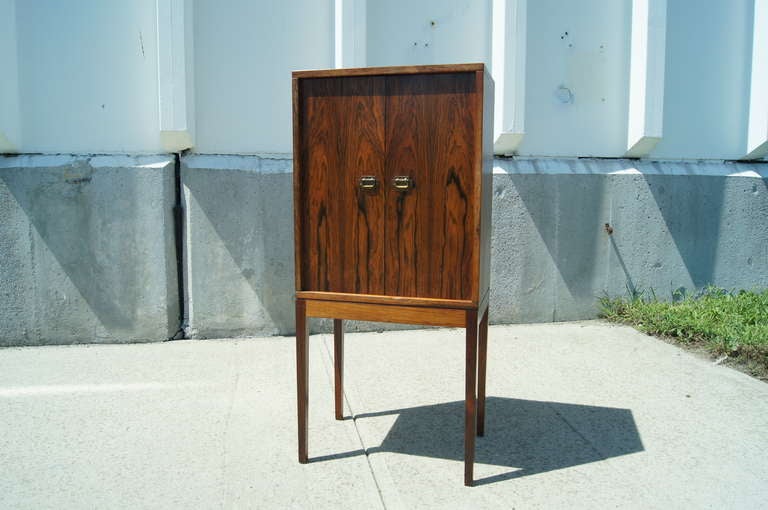 This diminutive cabinet by Ole Wanscher was originally designed as a smoking cabinet. The two doors open to reveal 24 slots for pipes, two small drawers, and a mirror. Though intended for tobacco paraphernalia, this cabinet would make an excellent