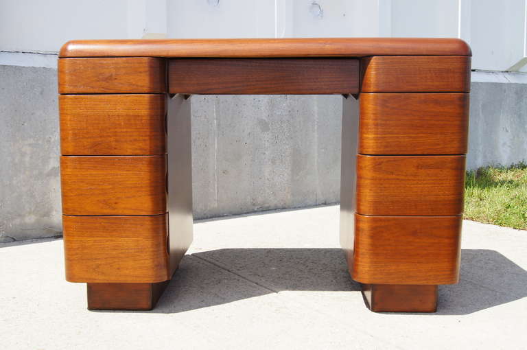 This desk was designed by Paul Goldman in 1946 and manufactured by the Plymold Corporation of Lawrence, Massachusetts. It is constructed of molded plywood and features one shallow center drawer and four graduated drawers on either side.