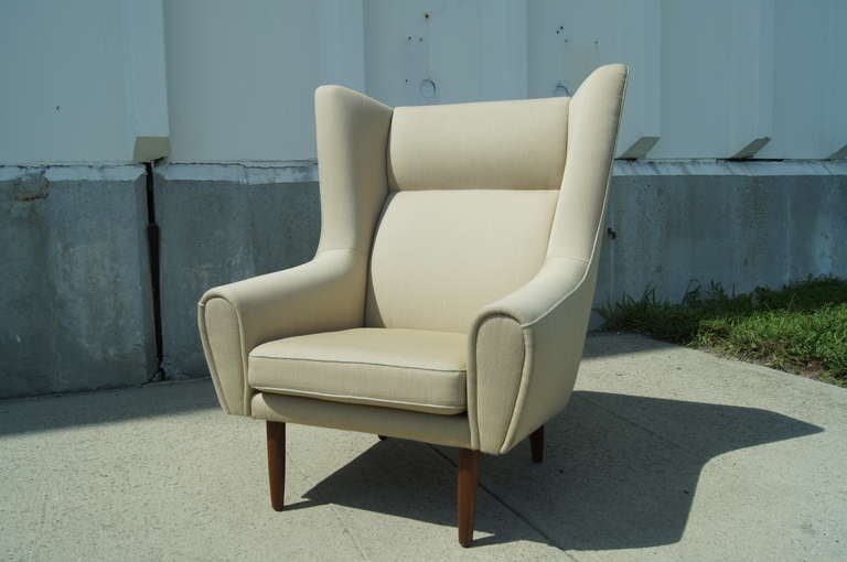 This armchair is a modern take on the traditional wingback. It features all original upholstery and tapered teak legs.