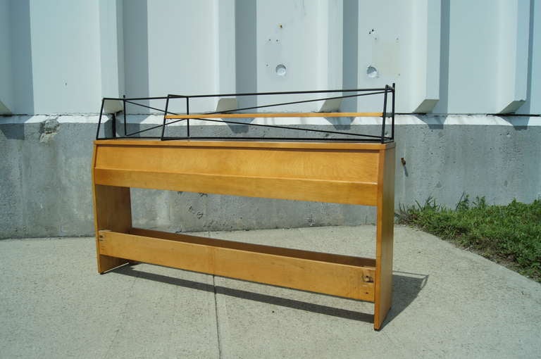 Paul McCobb designed this solid maple headboard, model 1553, as part of the Planner Group line for Winchendon Furniture. The frame fits a full-size bed and features bookcase shelving backed with slender wrought iron rods.

Maker's mark on back.