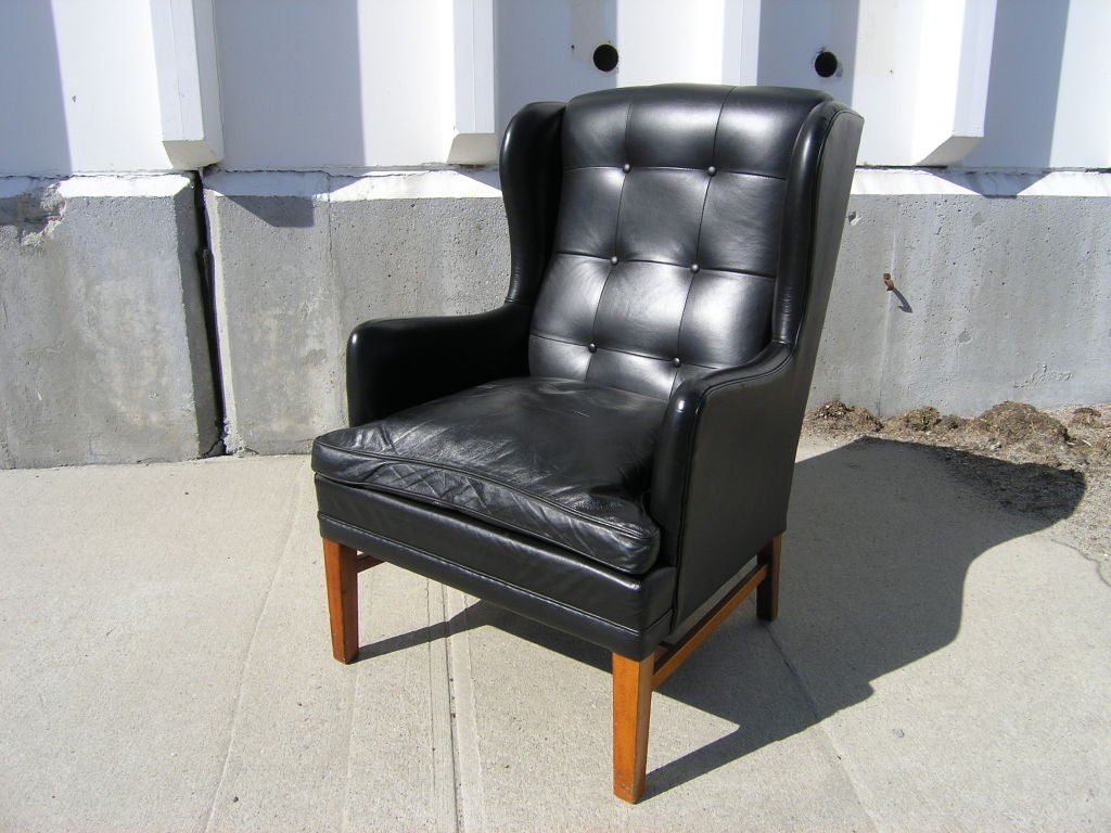 This high-back armchair, attributed to the Danish furniture company Fritz Hansen, combines comfort with Scandinavian style. It is upholstered soft black leather.