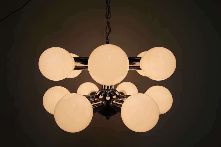 This muscular space age pendant, an example of an Italian 1970s aesthetic, features a chrome frame with twelve large light globes, arranged in two staggered levels.
