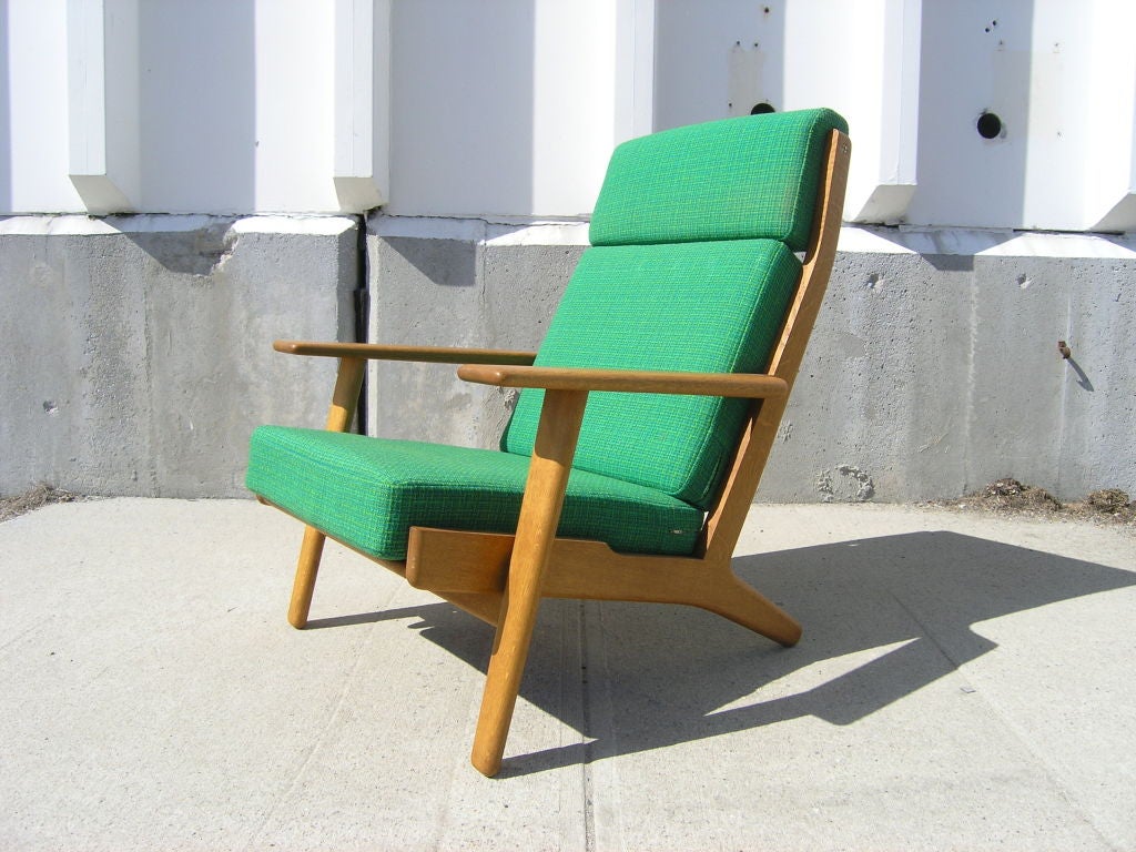 This classic high back lounge chair by Hans Wegner features wide paddle arms and is all original condition with vibrant green textile.