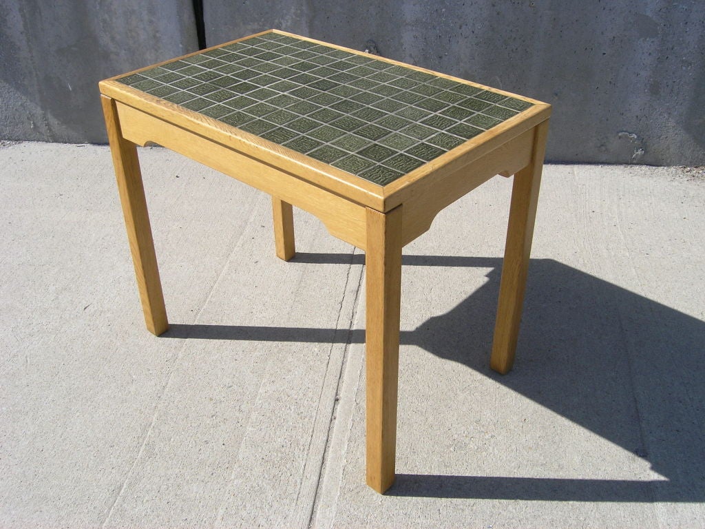 Designed by Hans Wegner for GETAMA, this mid-century side table features a grid of incised green ceramic tiles set into an oak frame, perfect for a sun room.

Maker's mark underneath.