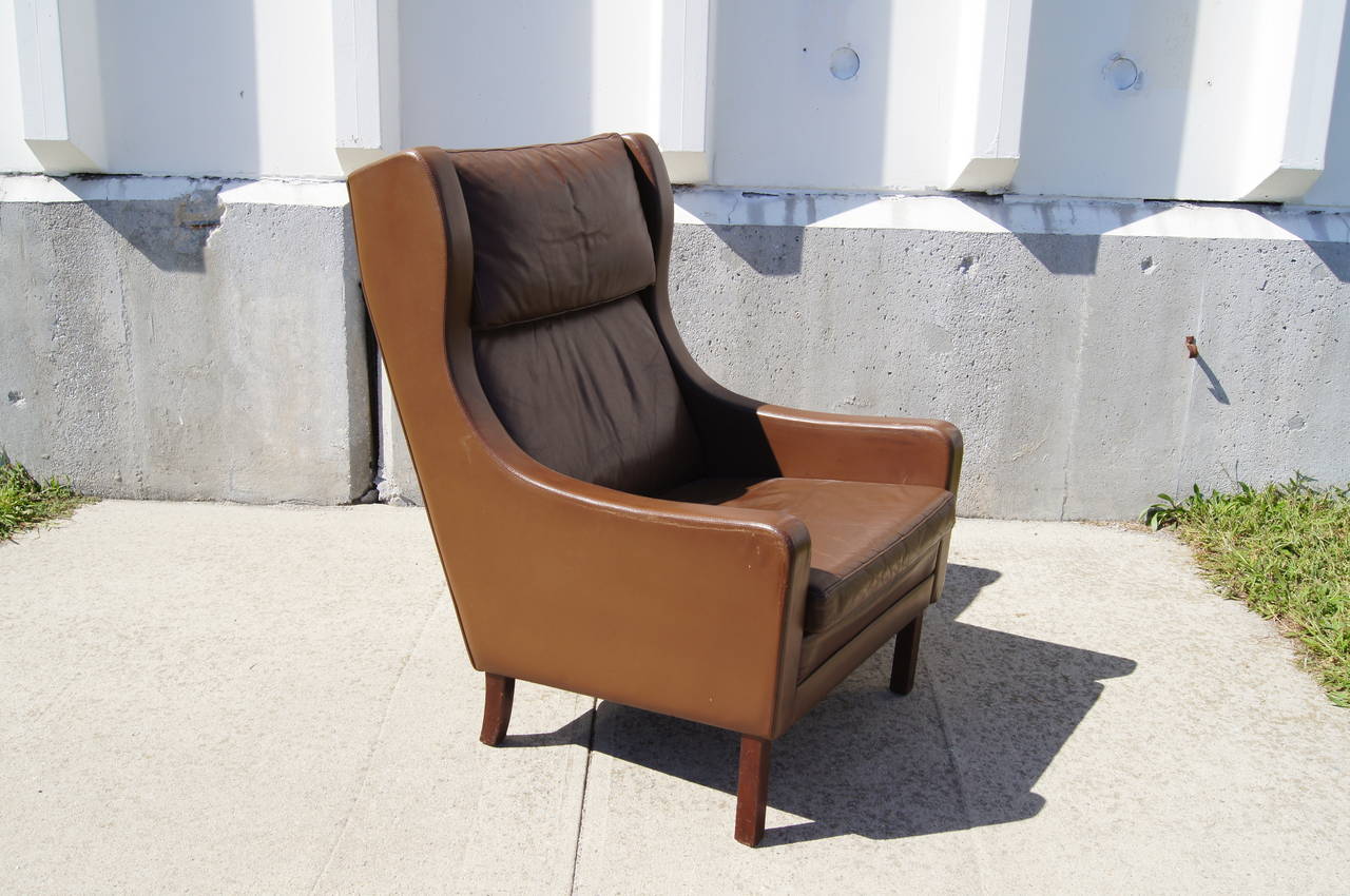 Designed in the style of Børge Mogensen, this well-constructed and deeply comfortable Danish modern lounge chair features a solid wood frame upholstered in patinated brown leather.