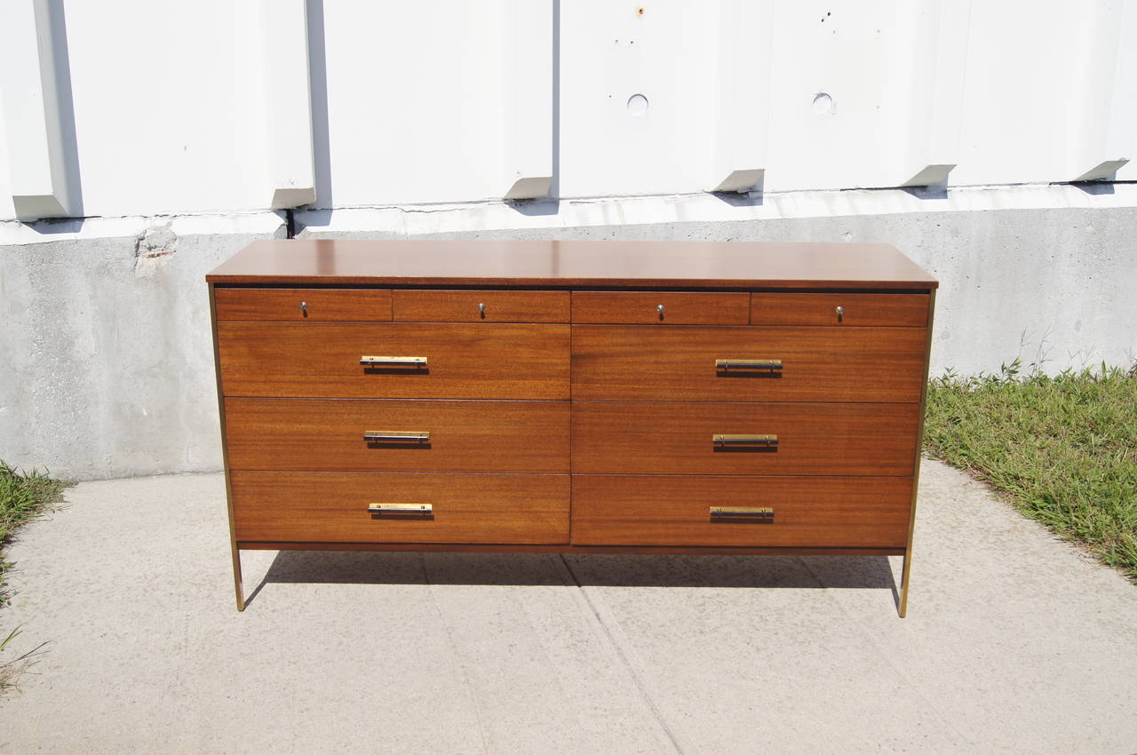 This dresser was designed by Paul McCobb and manufactured by Calvin furniture. It is constructed of mahogany with a brass frame and brass accents. The dresser has six large drawers and four small drawers. Original label is intact.