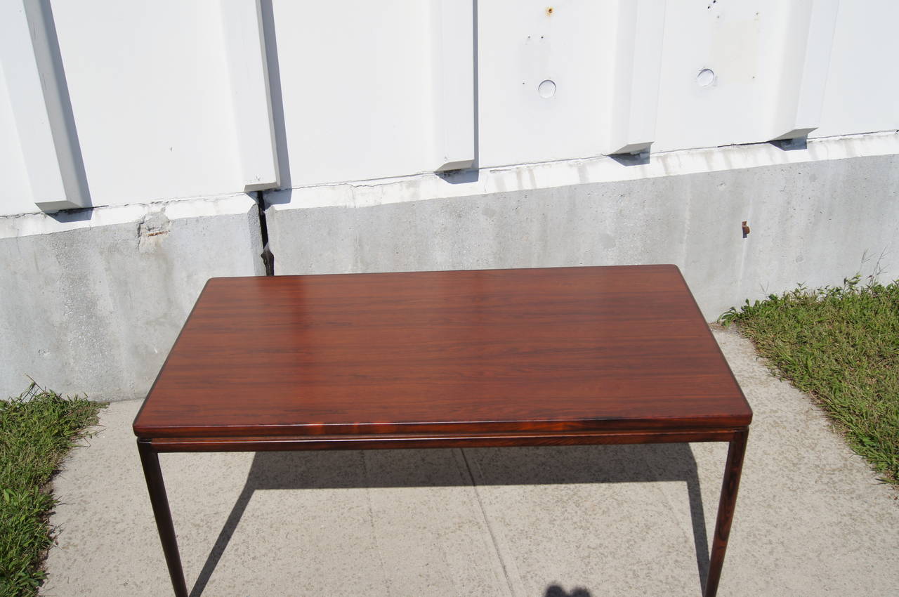 This beautiful dining table features a simple design by Johannes Andersen and rich rosewood grain. The table includes two leaves that rest on supports that pull-out from the sides of the table, thus allowing the top to be seamless.