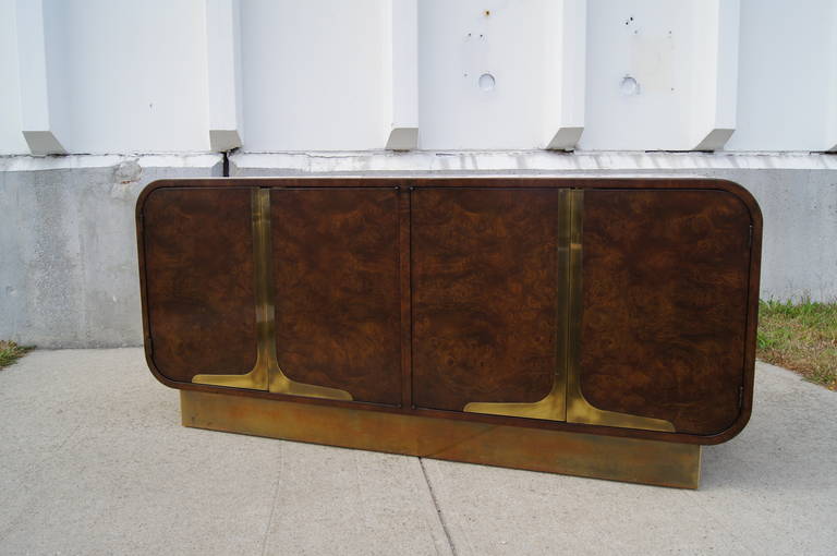 Designed by William Doezema, a cofounder of Mastercraft, this handsome sideboard features dark amboyna burl wood with brass inlay along the top and sides and brass-trimmed doors. The case, which sits on a brass plinth, offers plenty of storage with