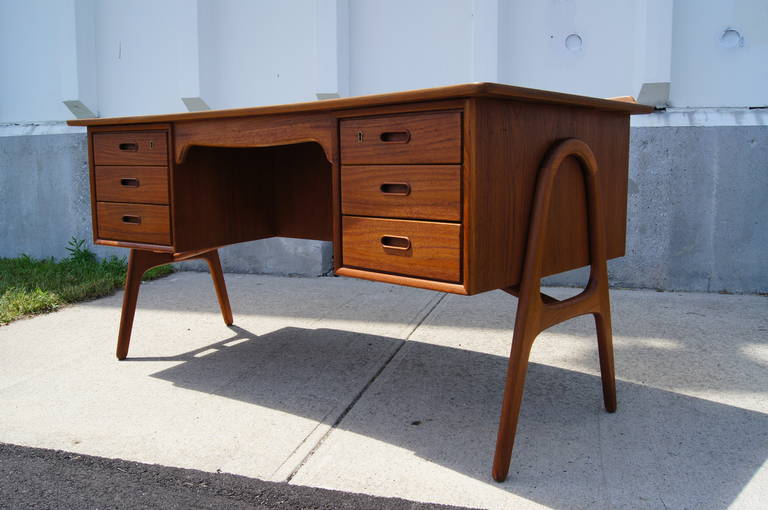 This teak desk by Svend Madsen features six drawers, an open bookshelf, and unique curvilinear details.