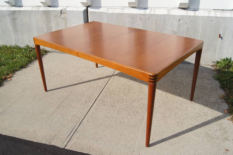 This dining table was designed by H.W. Klein and manufactured by Bramin Mobler. It is constructed of a teak top with round, tapered legs and rosewood joinery at the corners. The table includes one 23.75