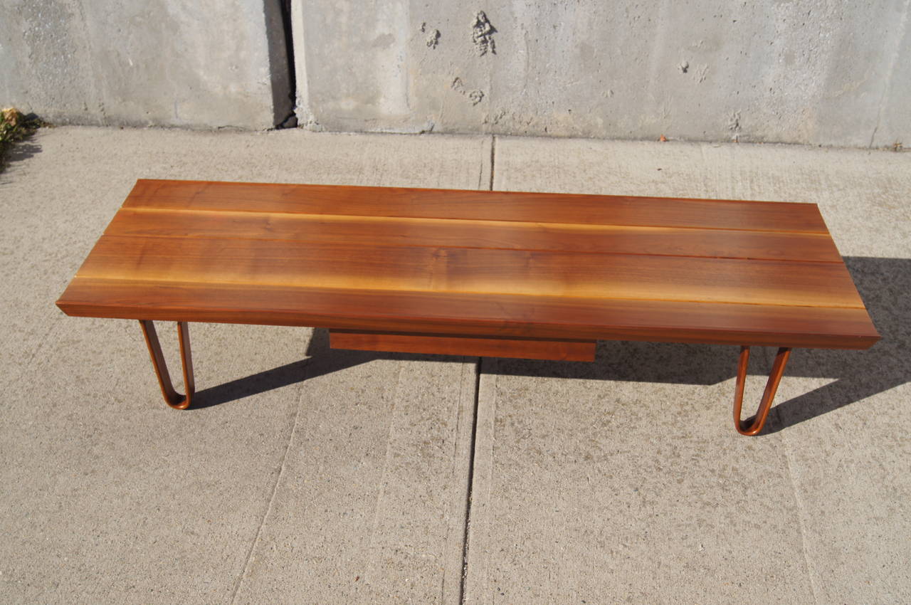 This table, model 4699, was designed by Edward Wormley and manufactured by Dunbar. It is composed of a soap grain walnut top and bent wood legs. It features one drawer with the original Dunbar table. This table could also serve as a bench.