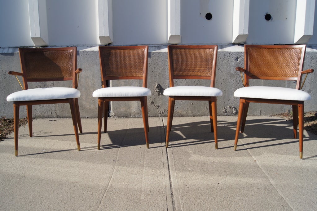 Attributed to John Stuart at Widdicomb, these lovely walnut dining chairs feature rattan backs and have been reupholstered in soft white faux leather. This set comprises two armchairs and two side chairs.