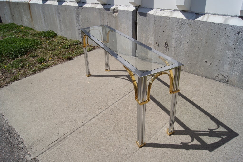This sleek Italian console table from the 1970s pairs a chrome and brass base with an inset glass top. It can equally serve as a sofa table.