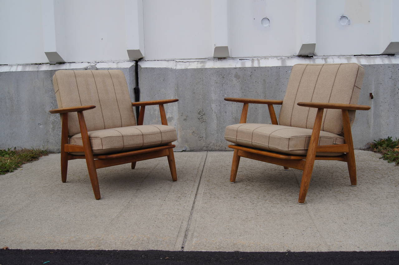 These armchairs by Hans Wegner for GETAMA, known as the cigar chair, feature a solid oak frame with original spring cushions and upholstery.