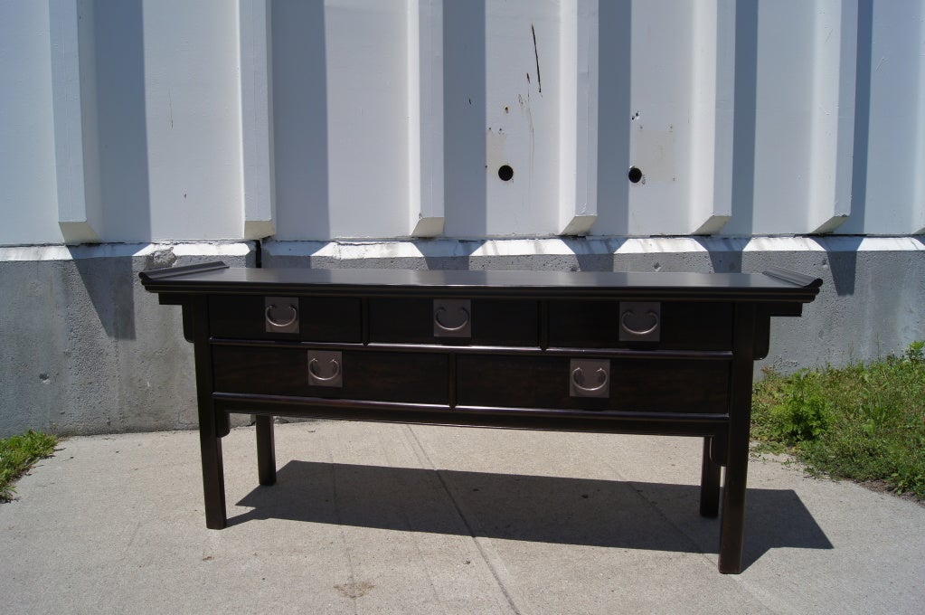 Made by century Furniture of Distinction, this ebonized console table features five drawers with bold pulls and a Silhouette that gives a subtle chinoiserie feel that will fit well in both contemporary and eclectic interiors.