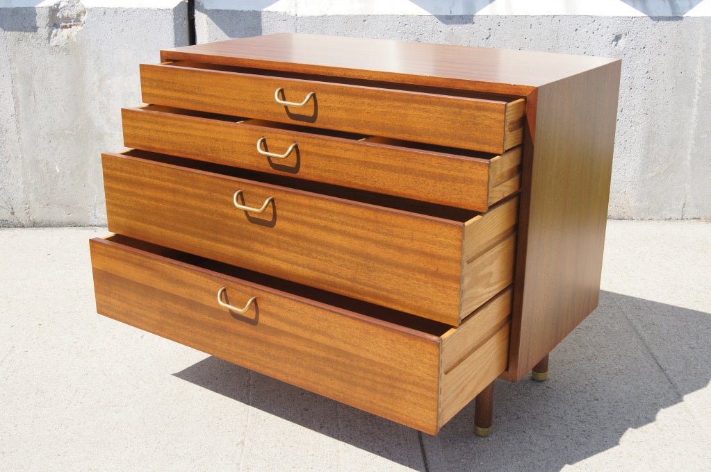 This clean-lined dresser by Harvey Probber features two deep drawers and two smaller drawers, the topmost of which is divided into three compartments. Brass drawer pulls and brass caps on the round feet complement the warm tone of the mahogany.