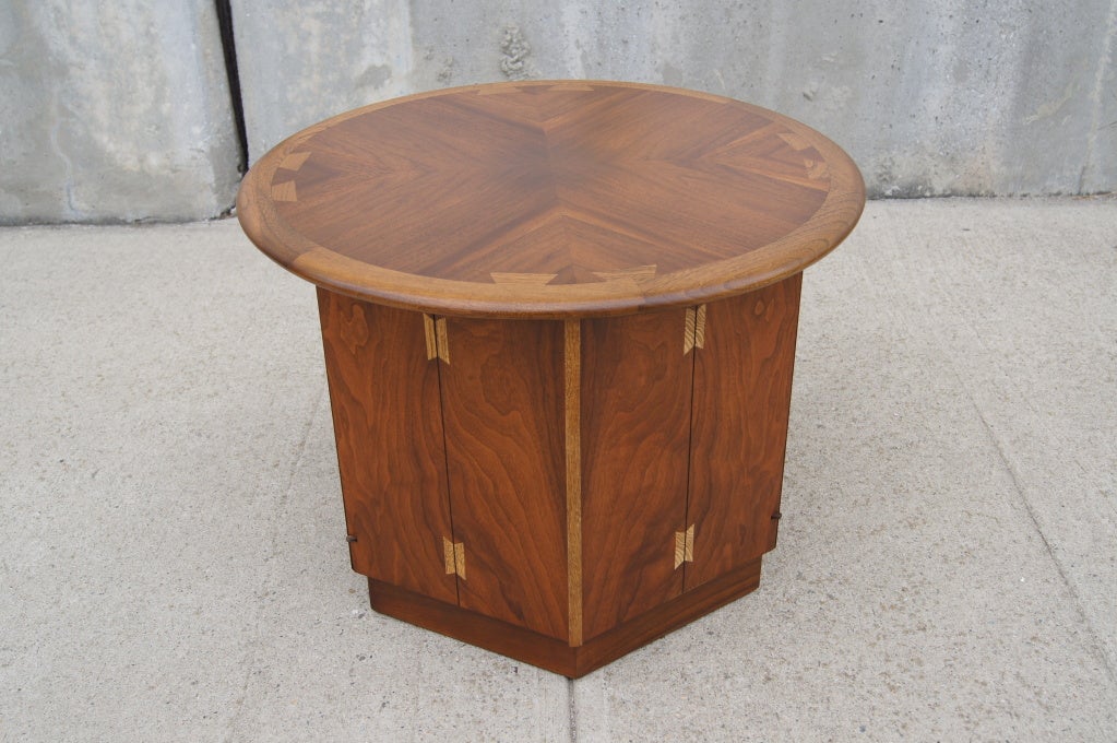 This fabulous side table by Andre Bus, for Lane's Acclaim series, places a round top on a hexagonal base that serves as a small cabinet with ample storage behind swinging doors. It features a beautiful walnut inlay with dove-tail joints.