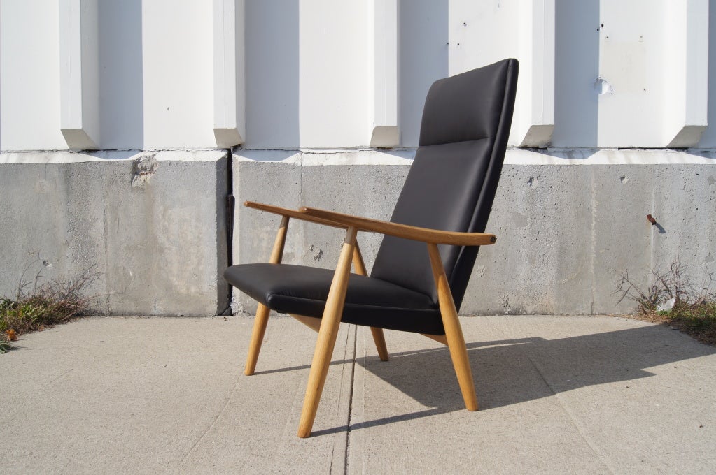 Hans Wegner designed this minimalist lounge chair, model GE-260A, for GETAMA in 1950. The solid oak frame supports a striking high back to which the tapered arms are attached with brass fittings. The spring coil system gives the chair a very