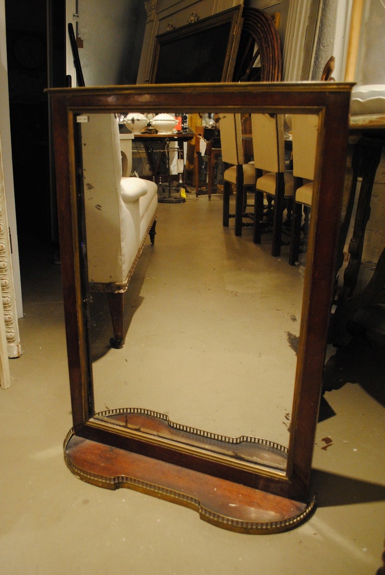 A mahogany mirror with attached shelf and brass gallery. Original glass and applied brass banding.