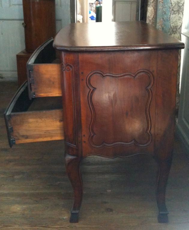 A beautiful two-drawer commode with a bow front, graceful carvings and hoof feet.