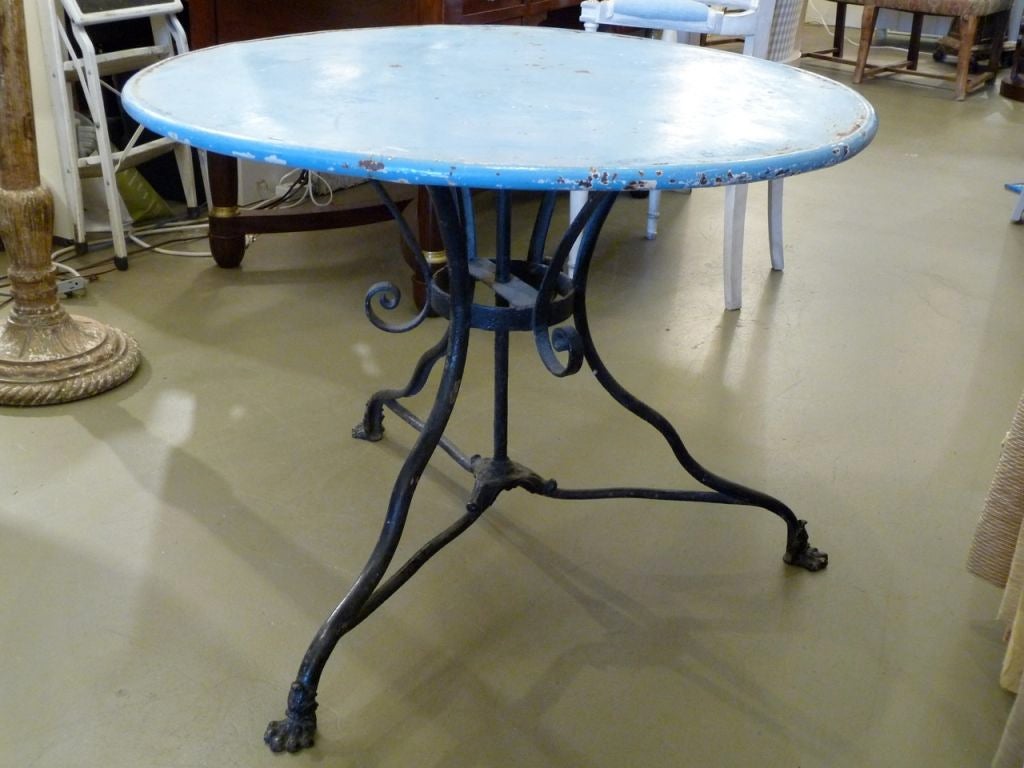 A wonderful blue and black cast iron cafe table with original paint. Iron paw feet.