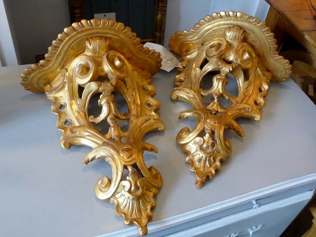 A wonderful pair of carved giltwood wall brackets with scroll decoration and scalloped carved tops.