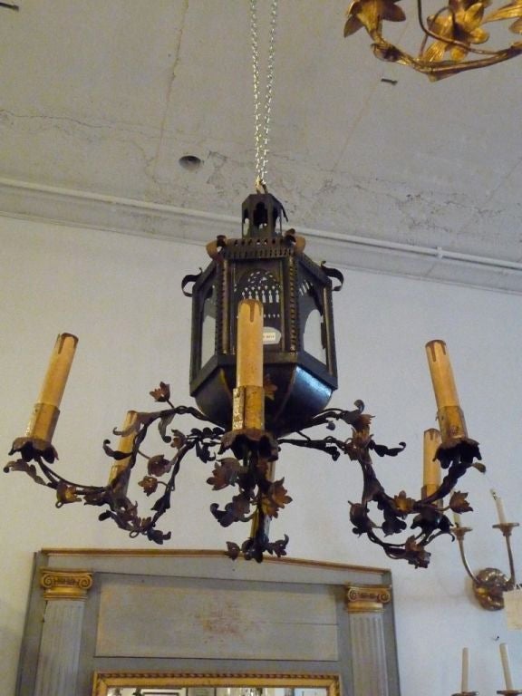 An unusual black tole six-arm chandelier with a six paneled pierced centre lantern retaining its original paint.