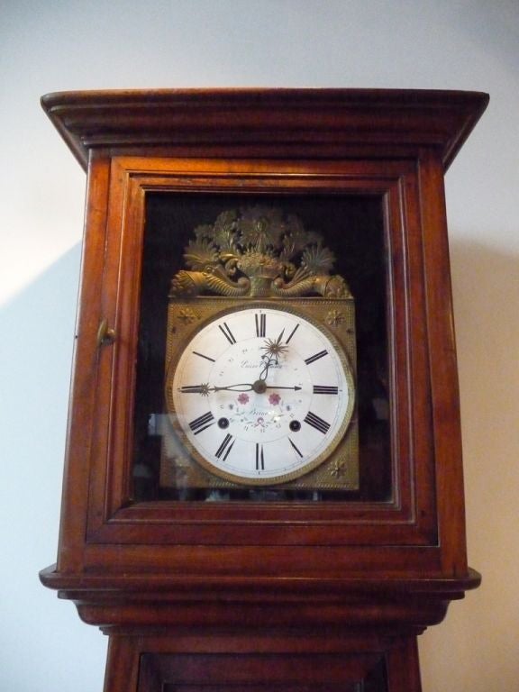 An unusual Norman fruitwood tall case clock on bracket feet with paneled inset doors.