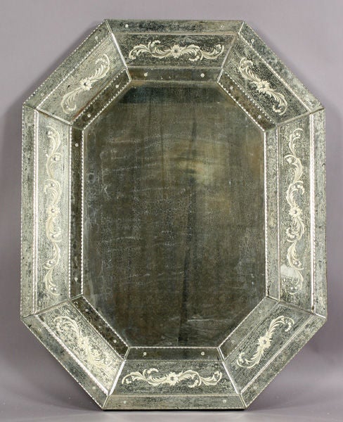 Venetian style mirror with etched and distressed frame around beveled central mirror panel.