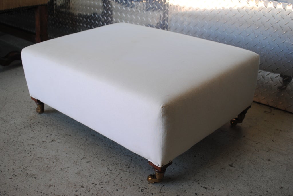 A low, rectangular custom ottoman on casters covered in muslin.