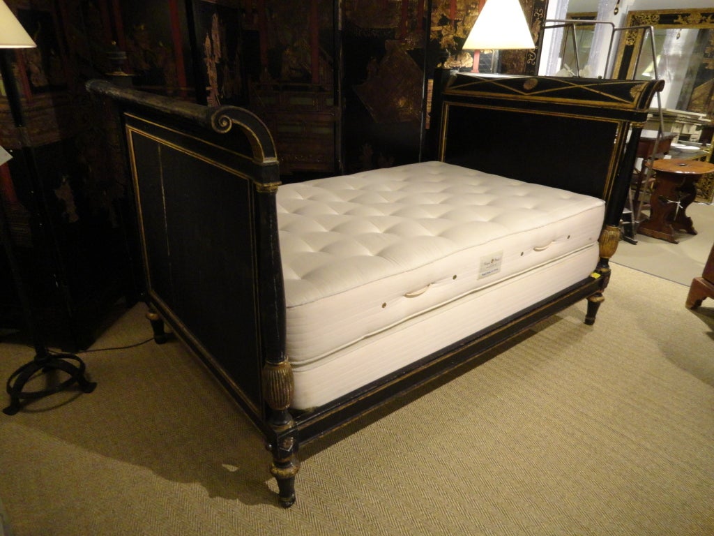 A period Directoire paint and gilt daybed with flared sides and decorative gilt accents in the neoclassical style. Original paint and gilding. Box spring and mattress are new and sold with bed.