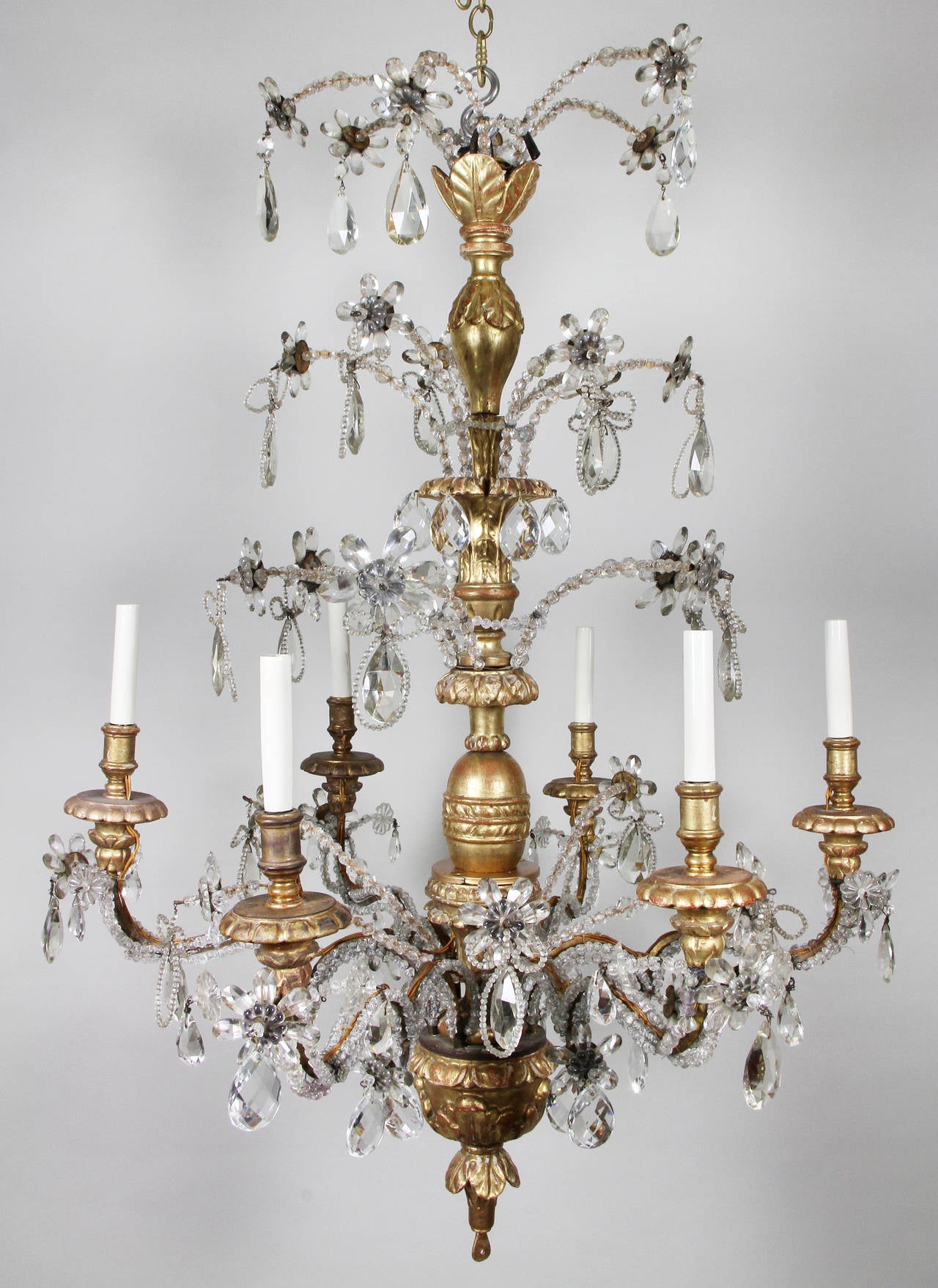 Carved giltwood central post with three-tiers of beaded stems terminating with flower heads over six giltwood candle arms with trailing beads and drops.