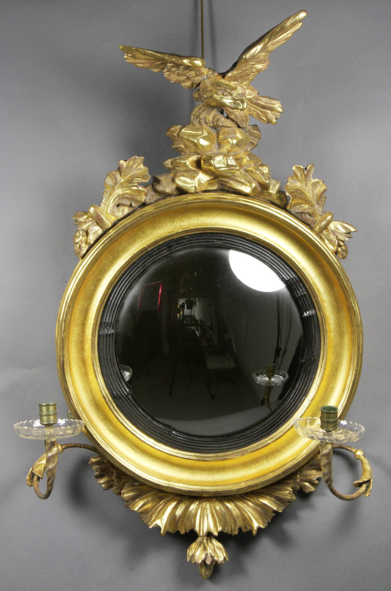 Typical form with eagle finial with rockwork surrounded by acanthus , round mirror with ebonized  reeded band , with pair of candle arms , base with leaf work and floral pendant.