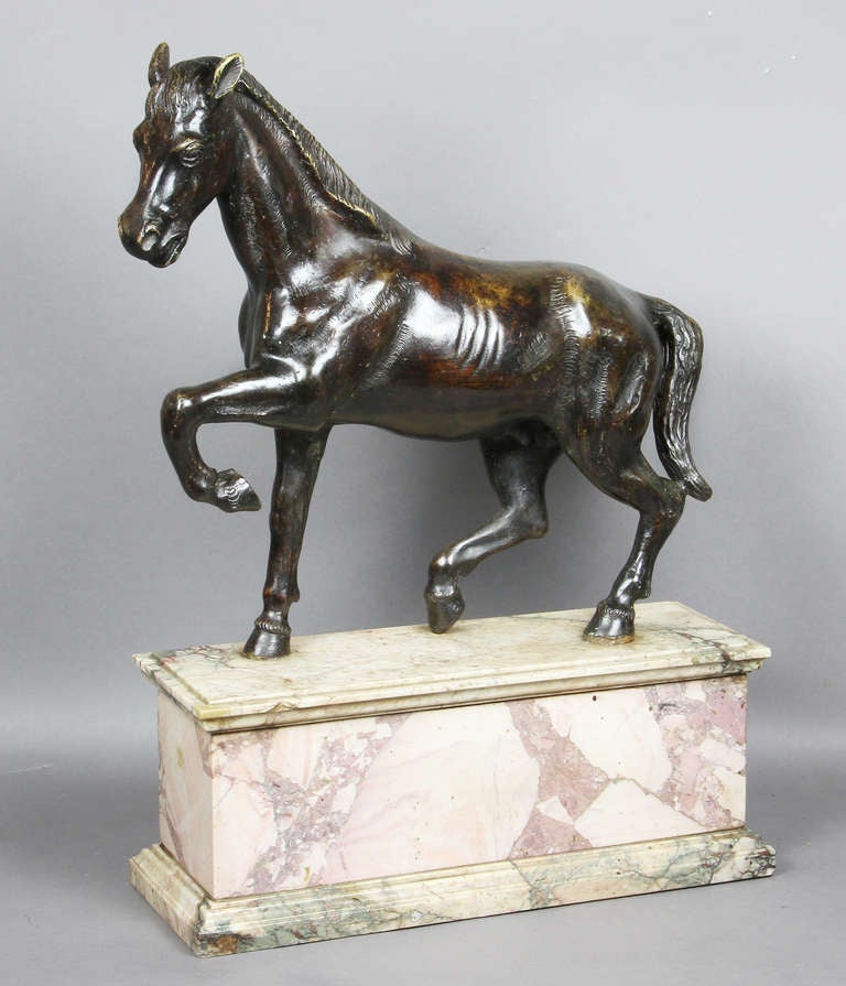 Horse with front left leg raised on a mottled marble base.