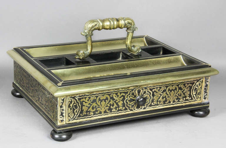 With scrolled cast handle over two bottle wells and two pen trays , over a drawer , bun feet.