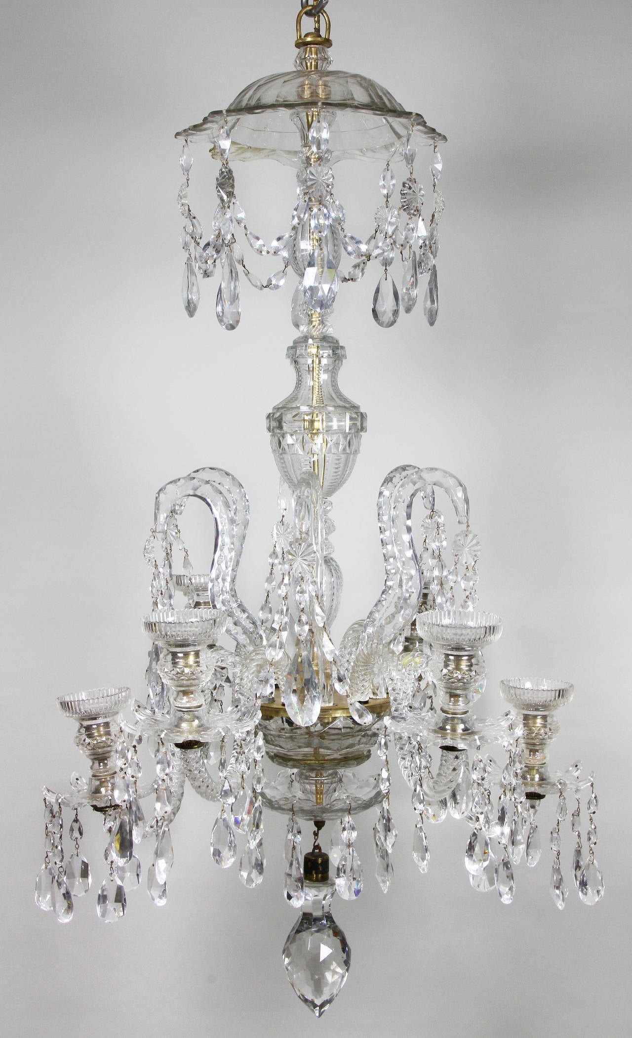 With canopy with suspended drops and cut urn form central support with six hooked arched arms with trailing drops over six candle arms two of probable later date, ending with a canopy and large faceted drop.