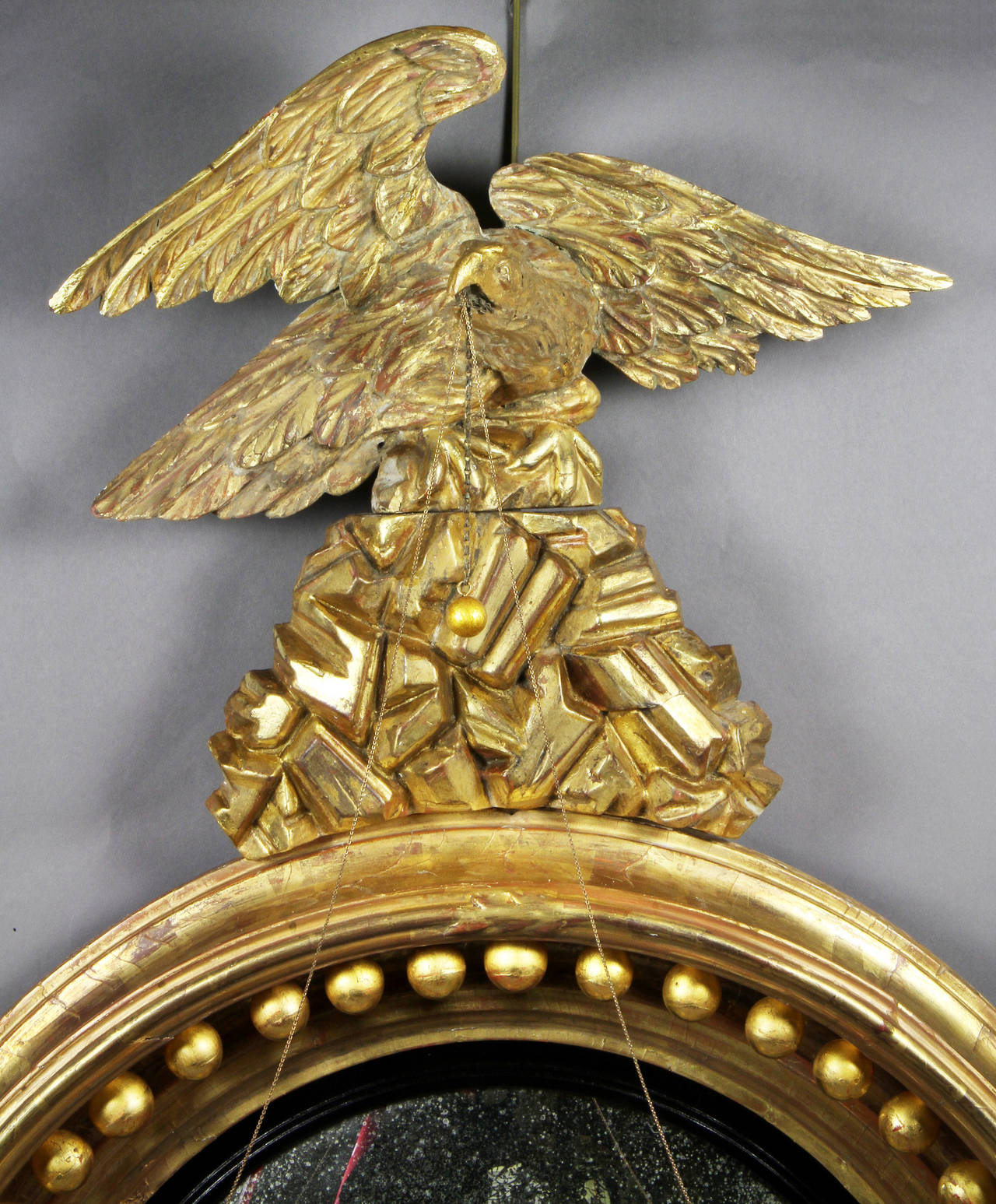 Eagle on rockwork superstructure over a convex mirror within an ebonized band and moulded frame with balls.