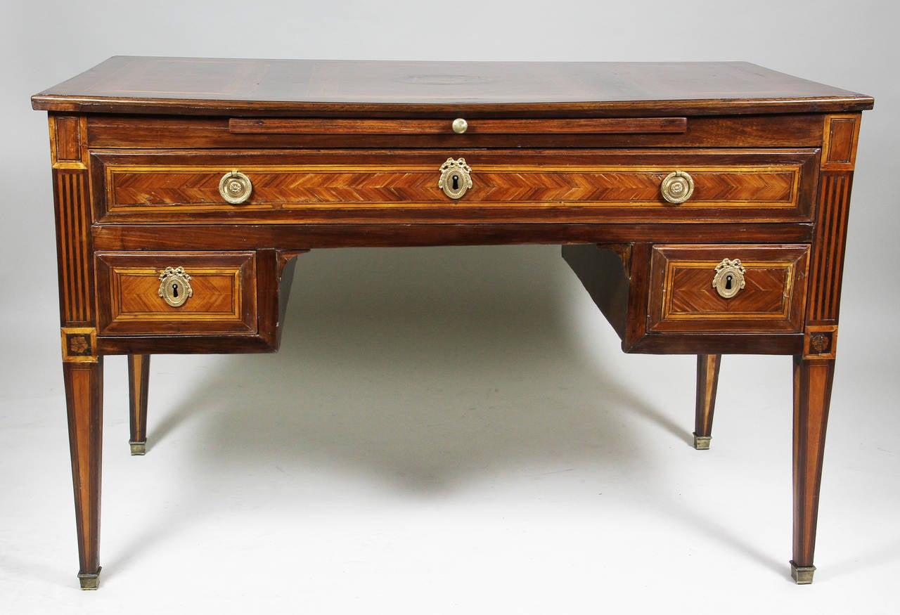 Rectangular top with central inlay over a writing slide and long drawer over two small drawers between a kneehole recess, raised on square tapered legs , sabot.