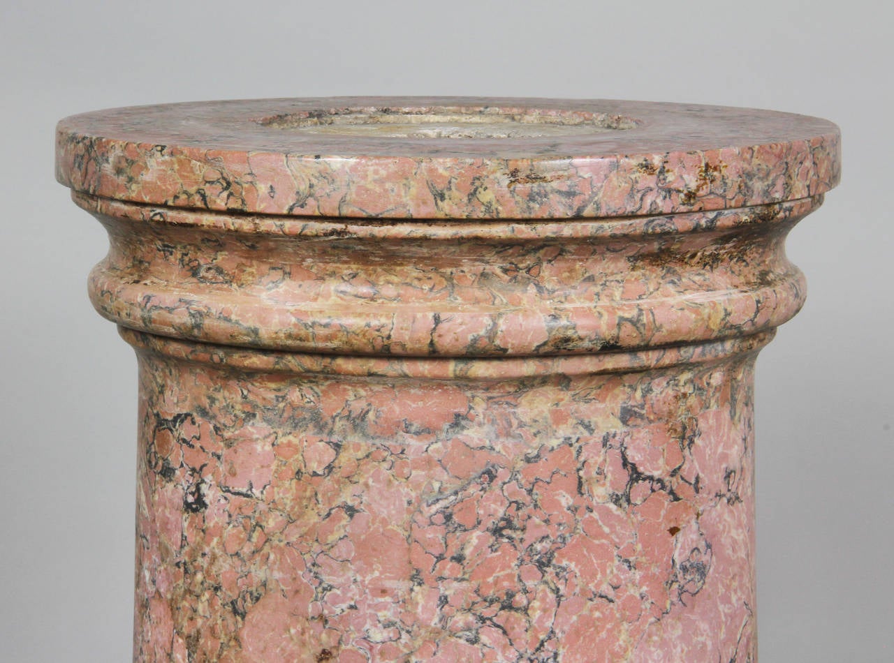 Cylindrical with a pink granite like finish , the base a faux Carrara. All one piece.