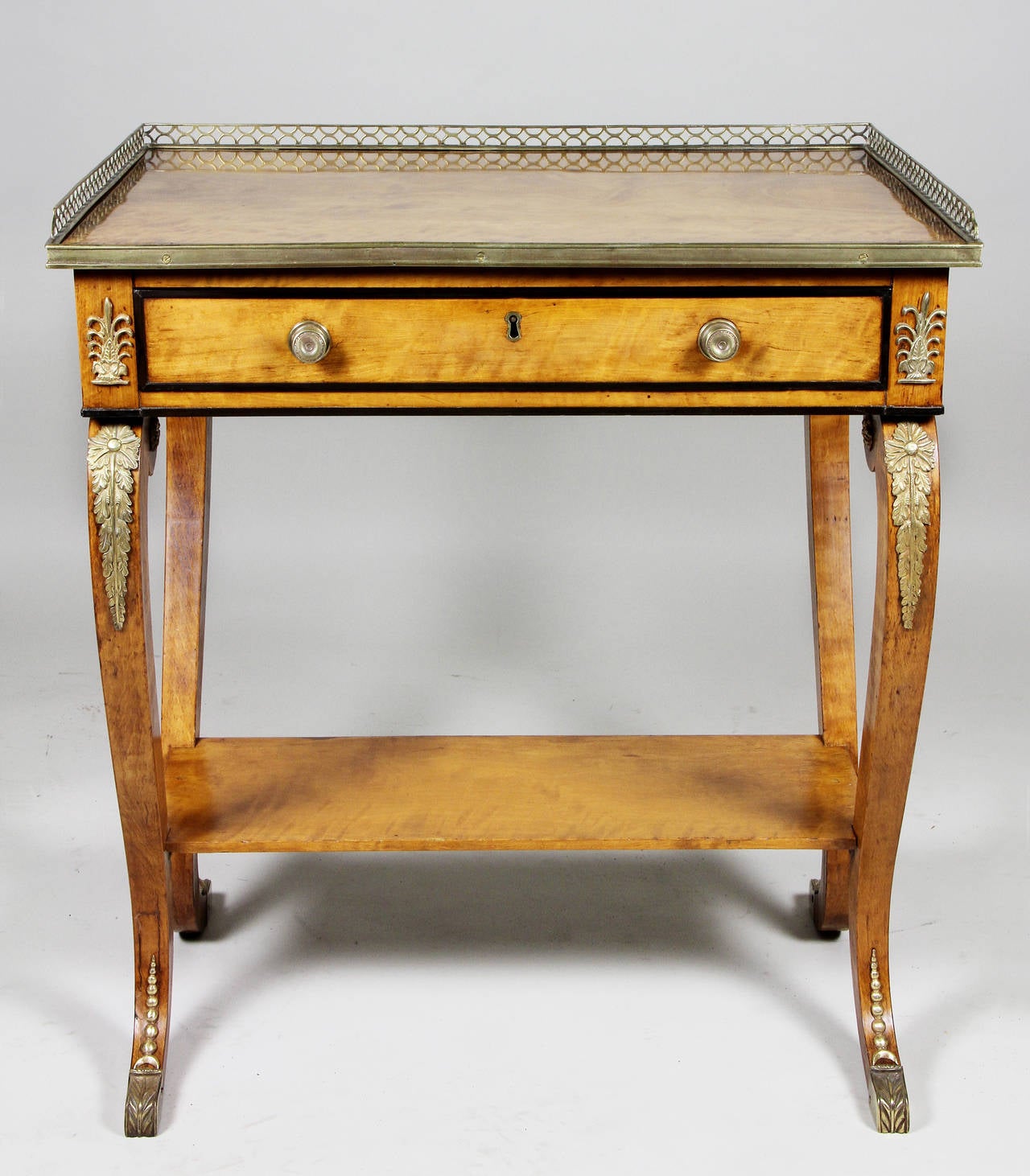 Rectangular with 3 /4 brass gallery over a drawer, in swept legs with lower shelf. Probably by Gillows of Lancaster.